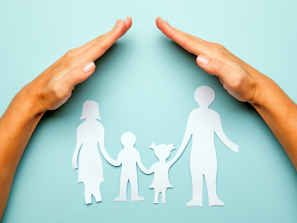 A hand sheltering paper cutouts of a family
