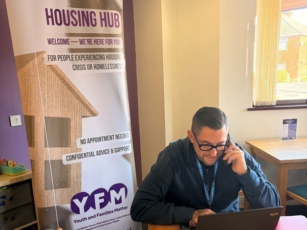 Photo of homelessness advisor sitting at desk in an office answering a telephone